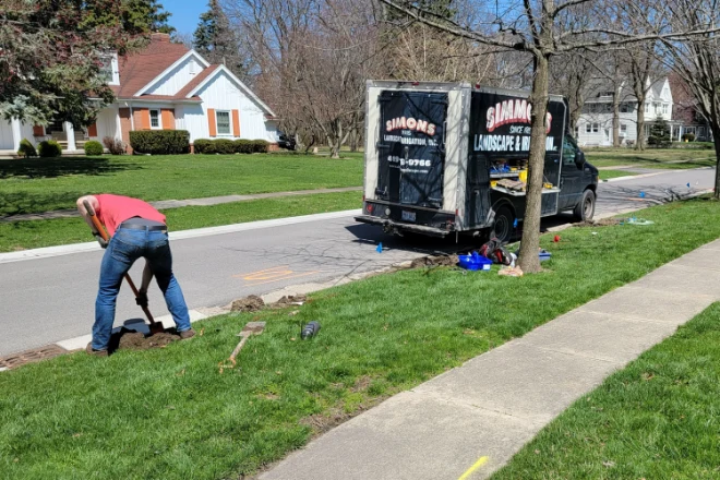 A man working on a lawn next to a truck.